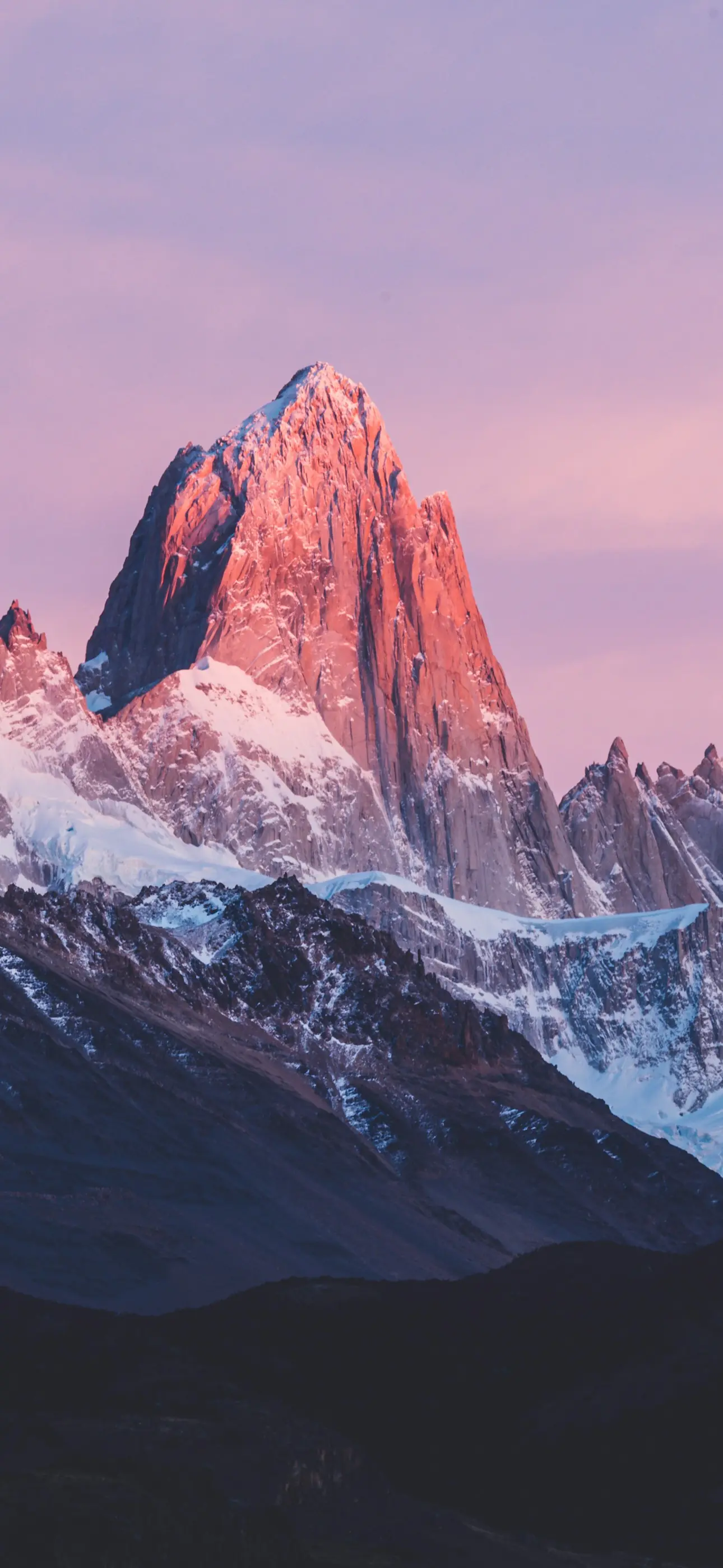 Fitz Roy at first light, its peak glowing coral above snow and dark ridges